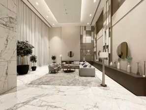 A modern living room with a marble floor, a sofa set, a coffee table, and a large potted plant.