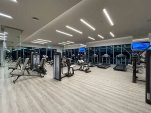 A modern gym with various exercise equipment, large windows, and a clean, well-lit interior.
