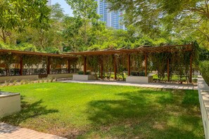 A covered outdoor area with a grassy lawn, wooden pergolas, and a pathway.