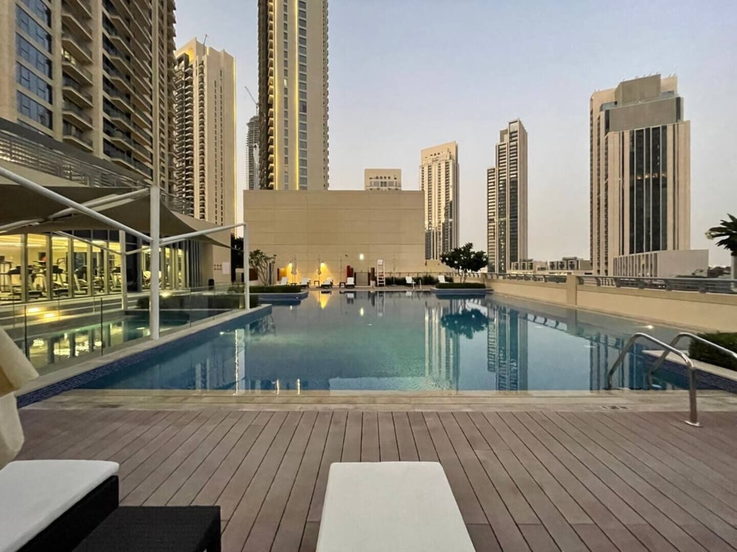 Una piscina en la azotea con sillas de descanso, rodeada de edificios altos.