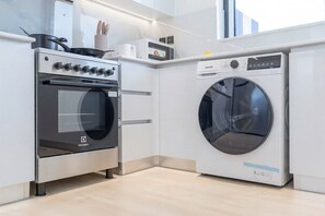 Una cocina moderna con horno empotrado y lavadora de carga frontal.