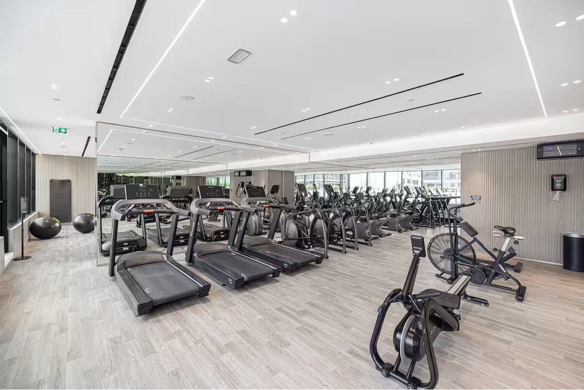 Een moderne sportschool met meerdere loopbanden, hometrainers en fitnessballen.