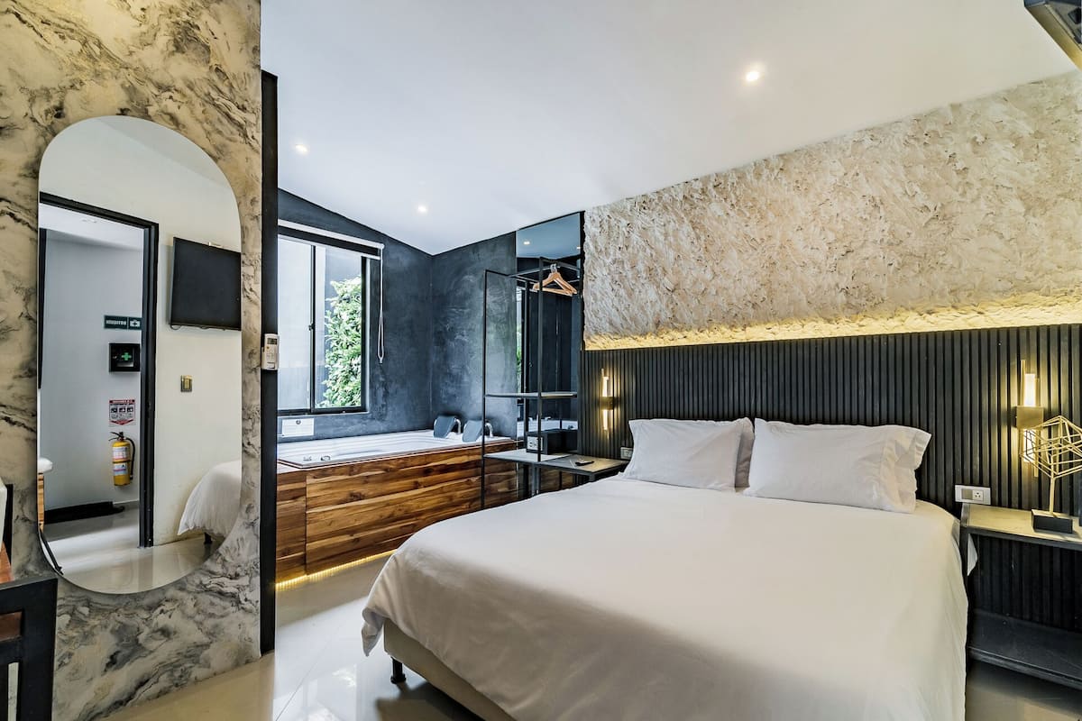 A modern bedroom with a large bed, a wooden vanity, a mirror, and a built-in bench.