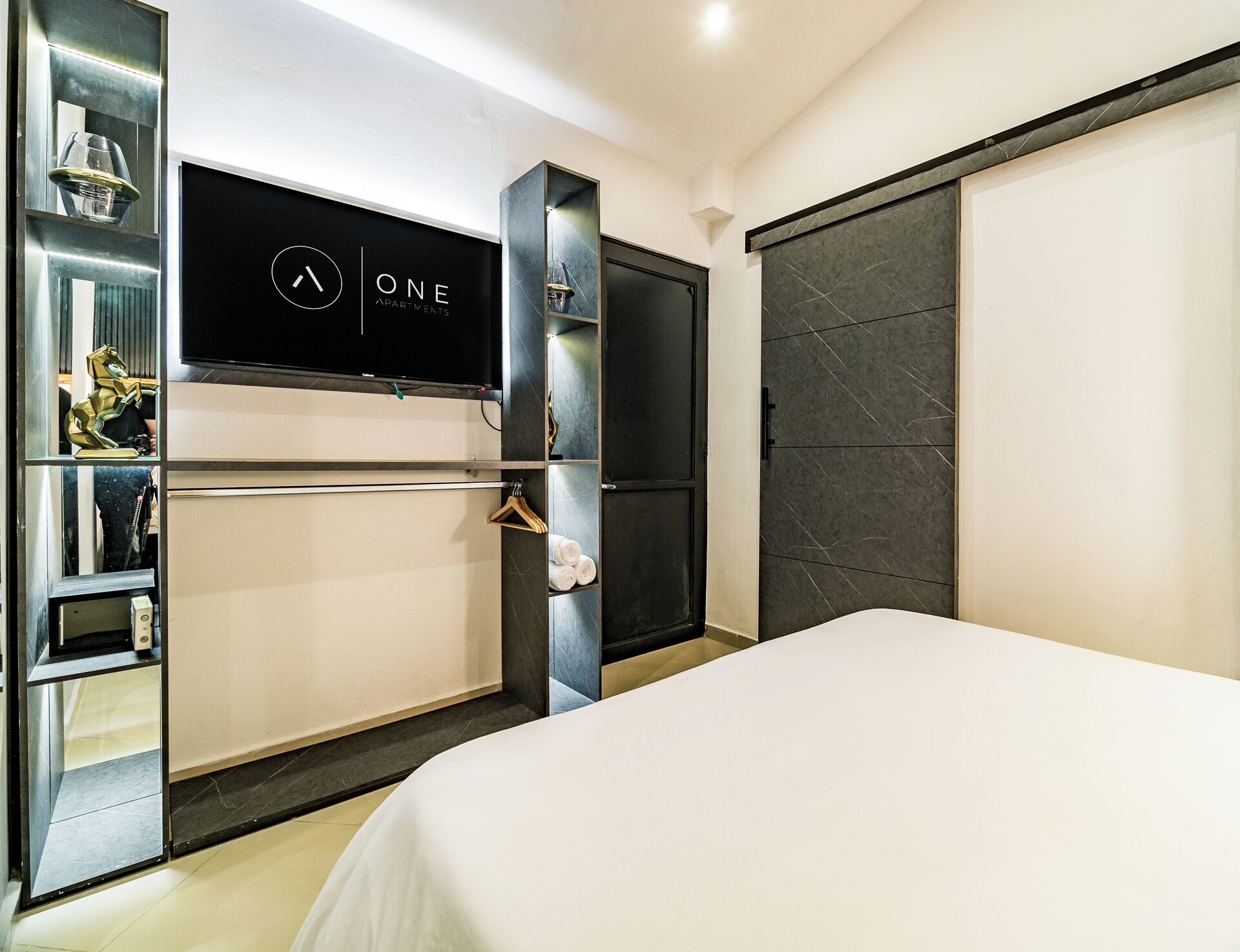 Een moderne hotelkamer met een bed, een televisie, een garderobe en een spiegel.