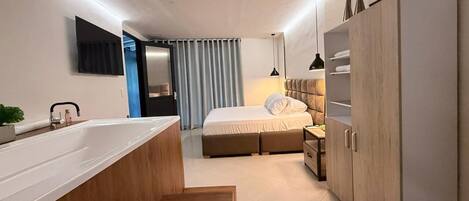 Un dormitorio moderno con una cama grande, mesitas de noche, un armario y un baño con bañera y lavabo.