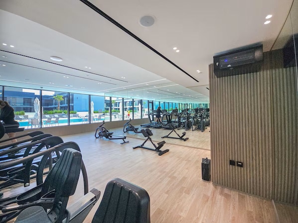 A gym with exercise equipment, large windows, and a view of the outside.