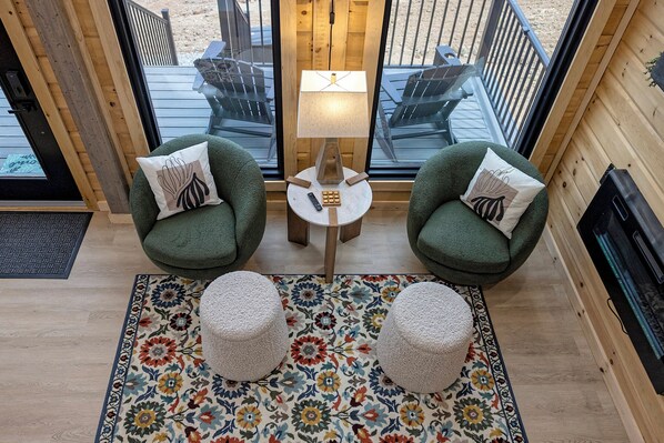 A cozy seating area with two green armchairs, a small round table, and a lamp. - The Fives - 22450 Cloud View Luxury Japandi Cabin (Bristol)