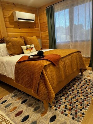 Una habitación estilo cabaña de madera con cama, almohadas, una colcha y un tapete.