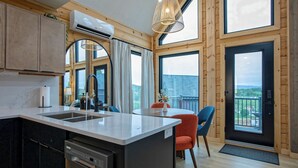 Una cocina moderna con una isla central, ventanas amplias y un balcón con vistas.