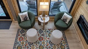 Una zona de estar acogedora con dos sillones verdes, una mesita redonda y una lámpara.