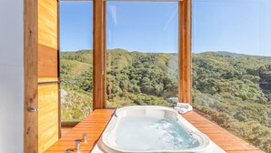 A wooden deck with a hot tub overlooking a forested hillside. - Incrível cabana vista da serra VST021 (Anitapolis)