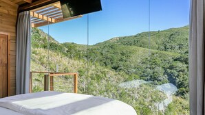 Een slaapkamer met een groot raam dat uitkijkt op een bergachtig landschap.