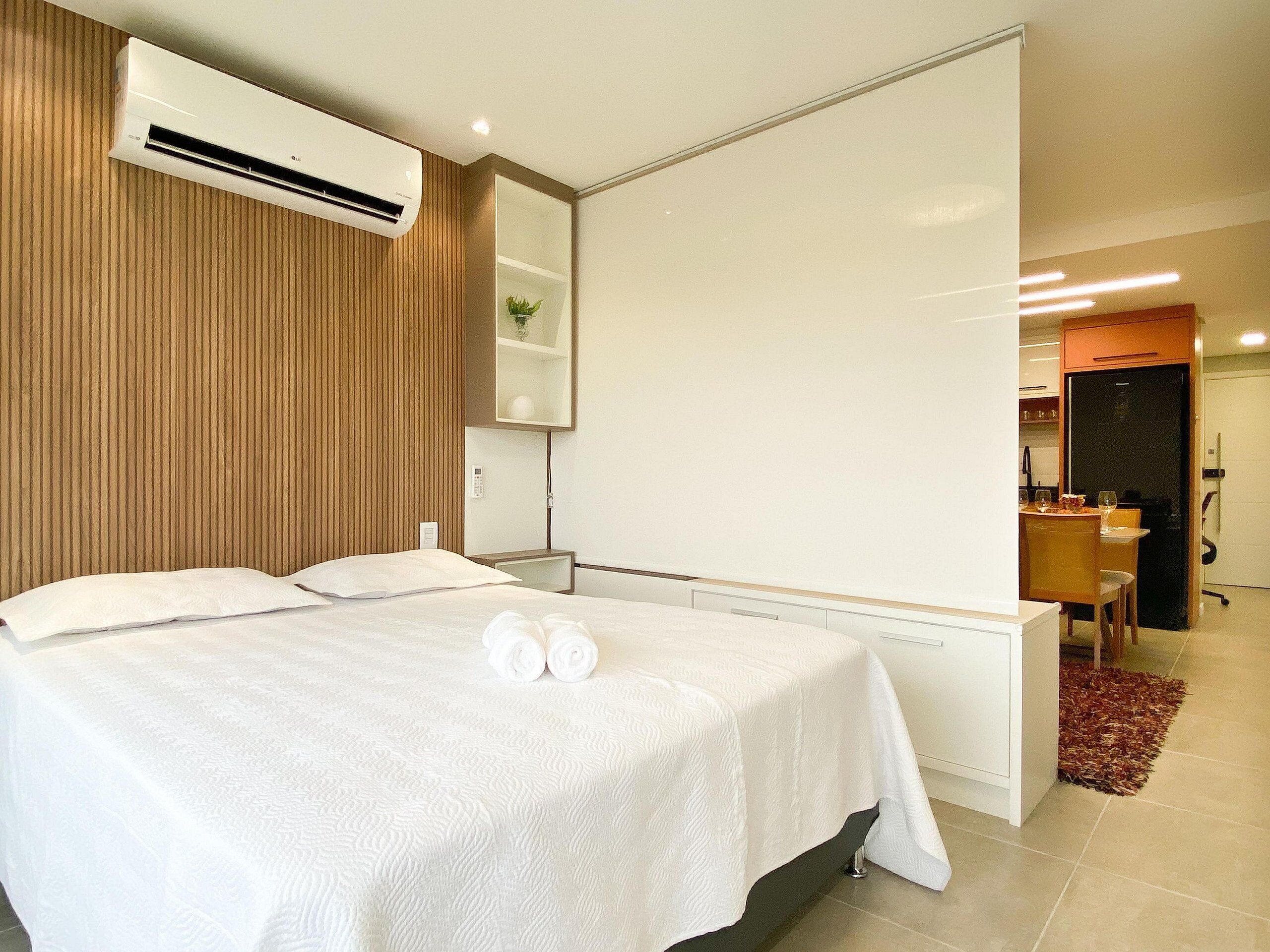 Una habitación de hotel moderna con una cama, una mesita y una pequeña cocina.