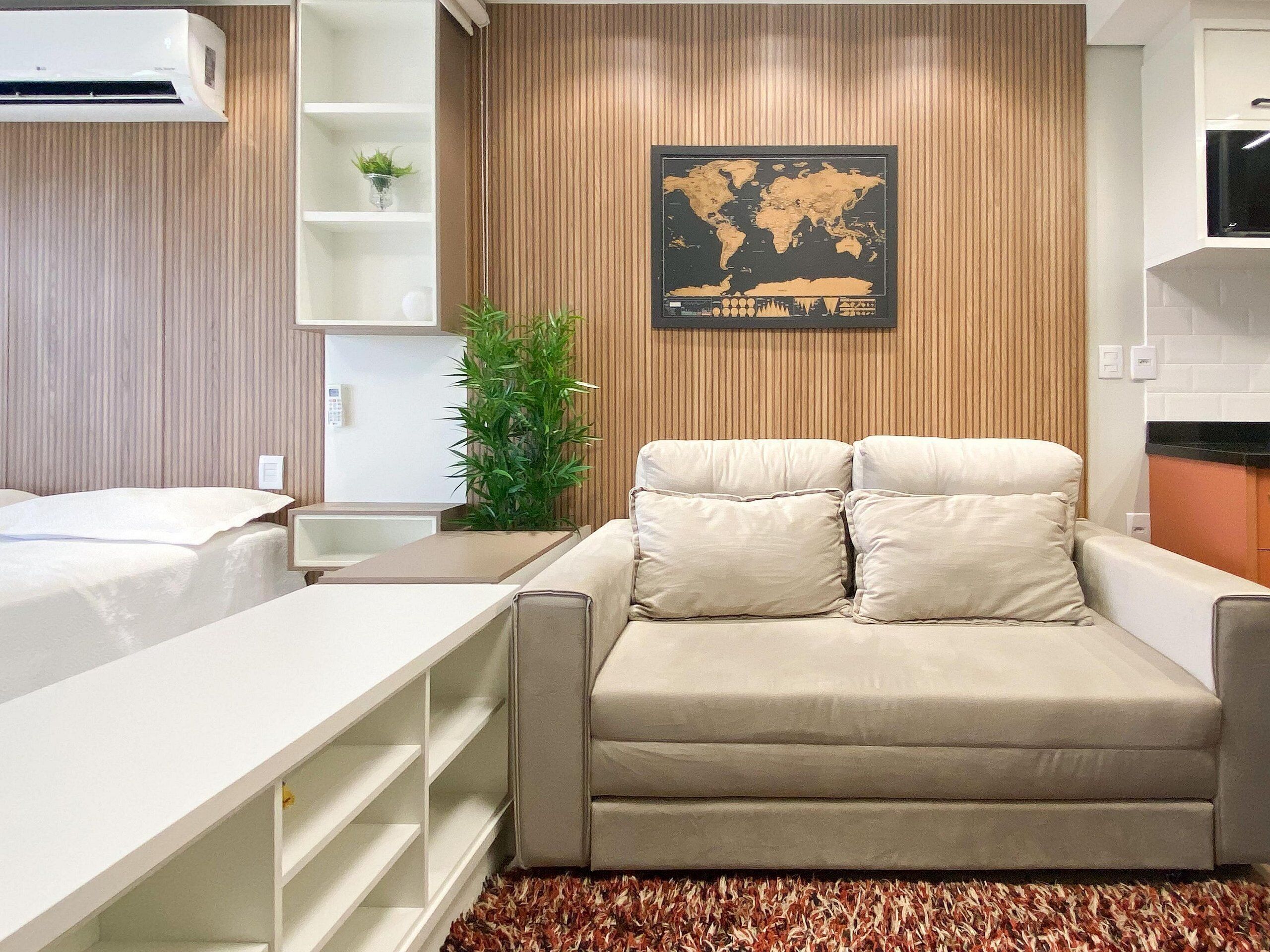 A modern hotel room with a sofa, a small table, a plant, and a world map on the wall.