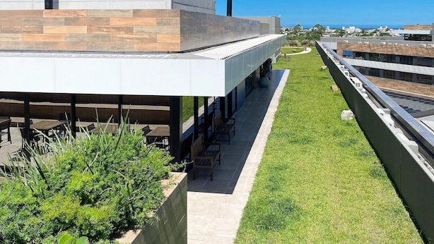 A modern building with a flat roof, outdoor seating area, and a view of the cityscape.