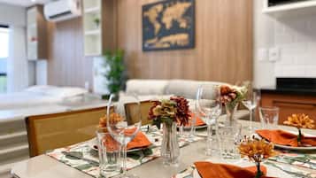 A dining area with a table set for four, featuring floral tablecloths, clear glassware, and orange napkins.