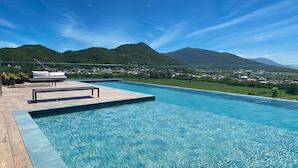 A clear blue pool with a wooden deck and lounge chairs, surrounded by lush greenery and mountains in the background. - Studio Shopping OKA Floripa - SOK232 (Florianopolis)