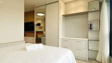 A hotel room with a large bed, a walk-in closet, a television, and a bookshelf.