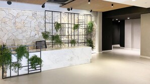 A modern lobby with a stone wall, a reception desk, and a staircase. - Studio Shopping OKA Floripa - SOK232 (Florianopolis)