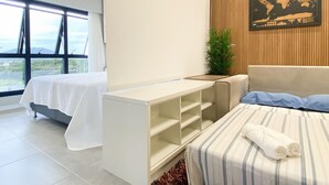 A modern hotel room with a bed, a bedside table, a large window with a view, a map on the wall, and a plant. - Studio Shopping OKA Floripa - SOK232 (Florianopolis)