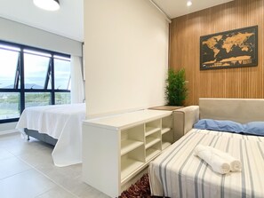 Una habitación de hotel moderna con cama, mesita de noche, ventana grande con vistas, un mapa en la pared y una planta.