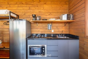 Una cucina compatta con frigorifero, microonde, fornello e forno.