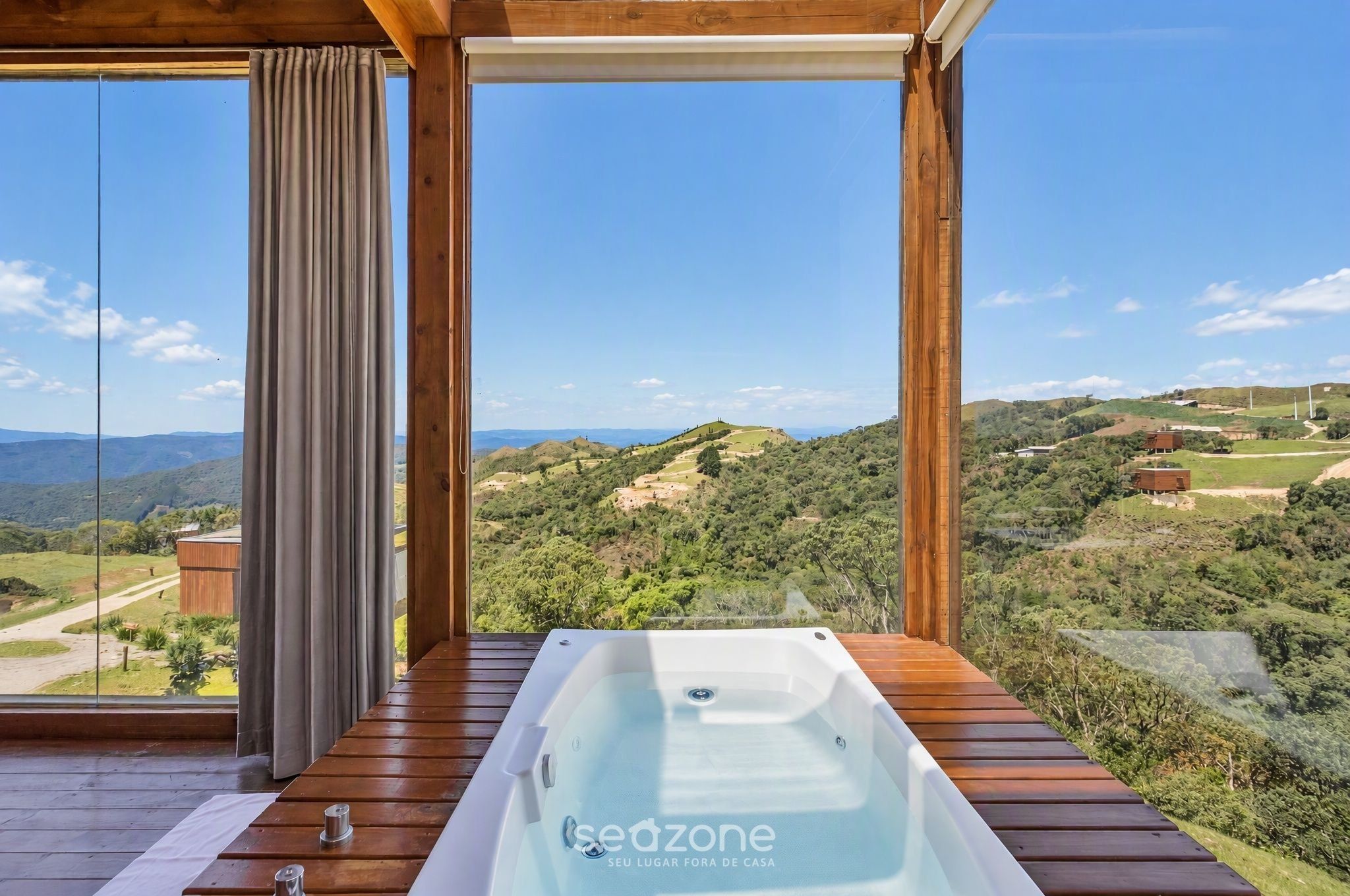 Una terraza de madera con un jacuzzi que da a un paisaje pintoresco.