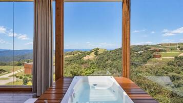 Una terraza de madera con un jacuzzi que da a un paisaje pintoresco.