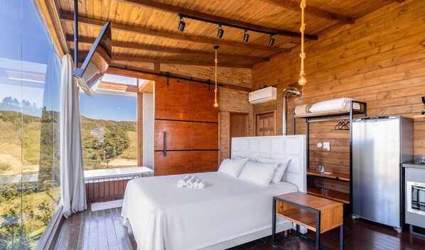 A bedroom with a bed, bedside table, and a view of the outdoors. - Cabana com vista e jacuzzi VST007 (Anitapolis)