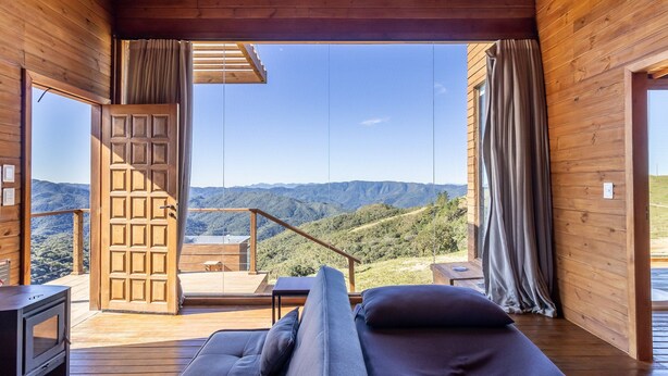 A wooden cabin with a balcony overlooking a mountainous landscape. - Cabana vista panorâmica e jacuzzi VST022 (Anitápolis)