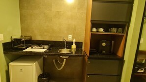 A compact kitchenette with a refrigerator, a sink, and a coffee machine. - CJC Short Stay Ilusion (Natal)
