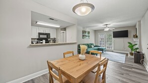 Ein Essbereich mit Holztisch und Stühlen, einem Deckenventilator und einer Küche im Hintergrund.