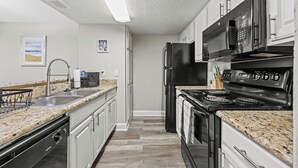 Eine moderne Küche mit Granit Arbeitsplatten, Edelstahlgeräten und weißen Schränken.