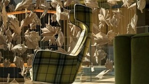 A modern chair with a unique design, a green sofa, and a wall with hanging leaf-like decorations. - Monverde - Wine Experience Hotel - by Unlock Hotels (Borba de Godim)