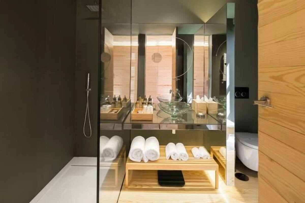 Une salle de bain moderne avec une douche à parois de verre, un meuble-lavabo en bois et des serviettes soigneusement pliées.