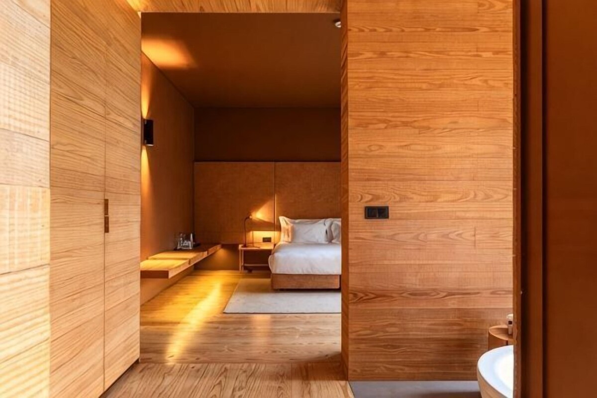 A wooden interior with a bed, bedside table, and a nightstand.