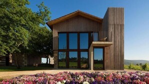 A modern building with large windows, a wooden facade, and a stone base. - Monverde - Wine Experience Hotel - by Unlock Hotels (Borba de Godim)