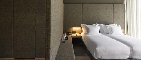 A modern hotel room with a bed, bedside table, and a nightstand.