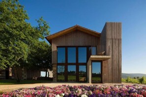A modern building with large windows and a wooden facade, surrounded by a garden with various flowers. - Monverde - Wine Experience Hotel - by Unlock Hotels (Borba de Godim)