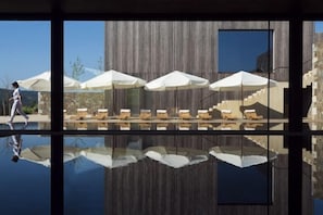 A poolside area with lounge chairs and umbrellas, a wooden building facade, and a clear reflection in the water. - Monverde - Wine Experience Hotel - by Unlock Hotels (Borba de Godim)