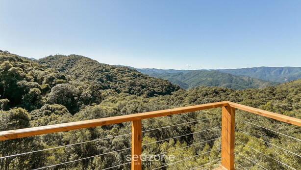 A wooden balcony railing overlooking a forested mountain landscape. - Cabana vista Serra Catarinense VST023 (Anitápolis)