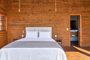 Ein Zimmer mit Holzwänden, einem Bett, Nachttischen und einem sichtbaren Badezimmer.
