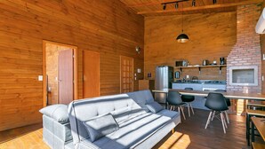 A cozy cabin interior with a sofa, dining table, chairs, and a kitchen area. - Cabana vista Serra Catarinense VST023 (Anitápolis)