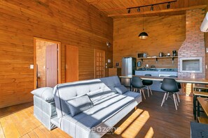 Un intérieur de chalet chaleureux avec un canapé, une table à manger, des chaises et un coin cuisine.