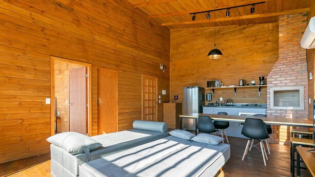 A cozy cabin with a wooden interior, a bed, a dining area, and a kitchen. - Cabana vista Serra Catarinense VST023 (Anitápolis)
