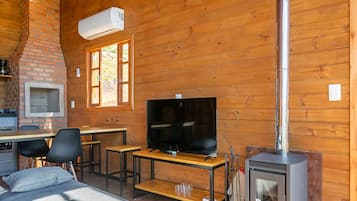 Een gezellig interieur met een stenen open haard, een televisie, een eethoek en een houtkachel.