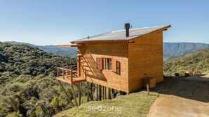 A wooden cabin with a balcony, set against a mountainous backdrop. - Cabana vista Serra Catarinense VST023 (Anitápolis)