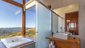 A bathroom with a large window, a wooden vanity, a sink, and a mirror. - Cabana espetacular região serrana VST008 (Anitápolis)
