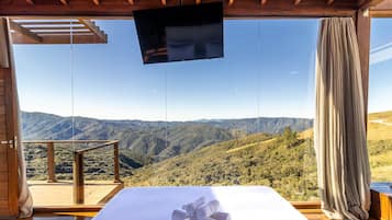 A bedroom with a large window overlooking a mountainous landscape.