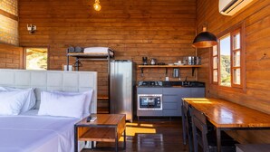 A cozy log cabin with a bed, kitchenette, and a dining area. - Cabana espetacular região serrana VST008 (Anitápolis)